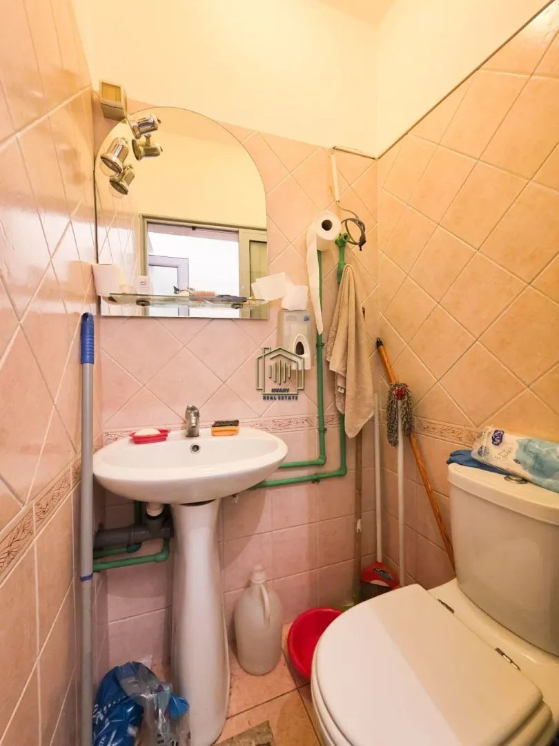Small bathroom tiled with ceramic tiles featuring a sink and a toilet.
