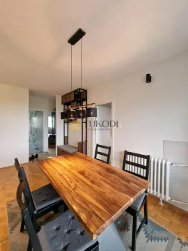 Dining area with a wooden table, black chairs, and a modern chandelier. - image 7