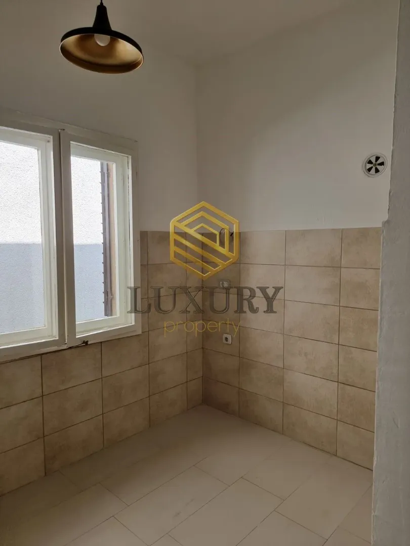 Empty kitchen with tiling and a window.