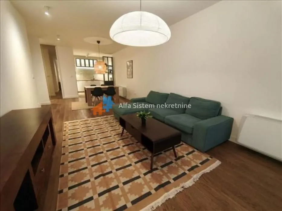 Living room with a sofa and dining area in the background.