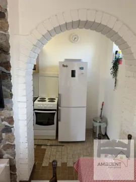 Manja kuhinja gledana kroz ukrasni lučni prolaz sa belim frižiderom i šporetom. - image 3