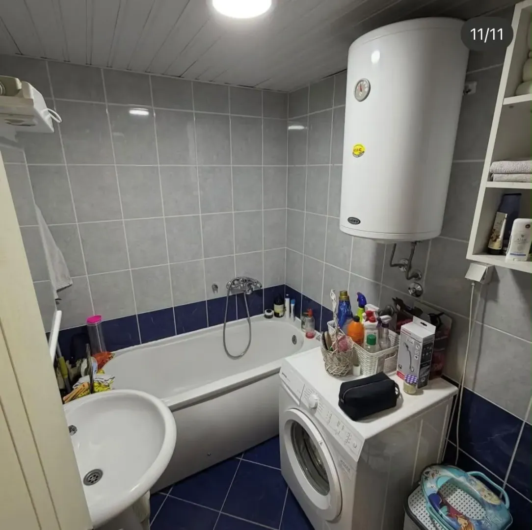 Small bathroom with a bathtub, washbasin, water heater, and washing machine.