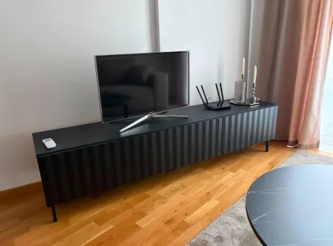 Living room with a black TV console and a television. - image 11