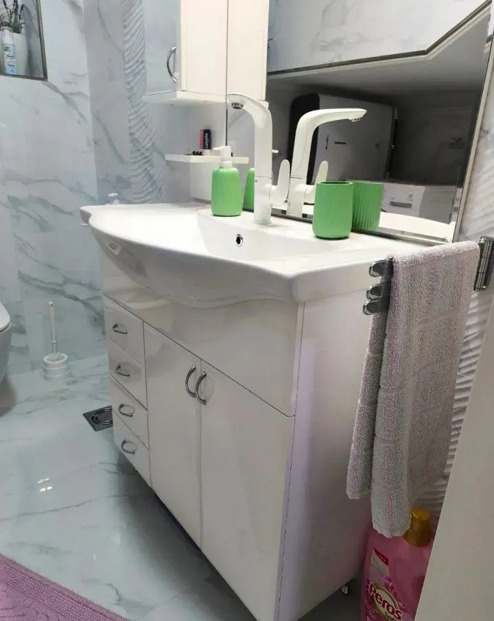 Moderno opremljeno kupatilo sa umivaonikom i ormarićem.