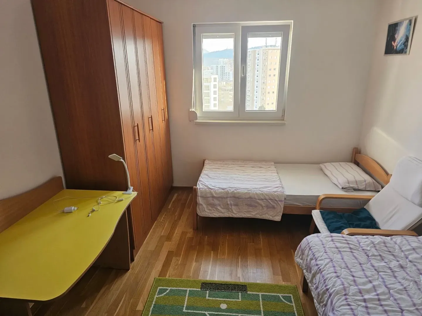 Furnished bedroom with a bed, wardrobe, and desk.
