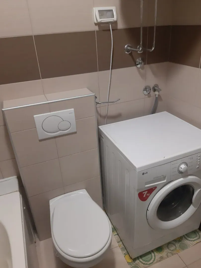 Dio kupatila sa toaletnom šoljom i veš mašinom.