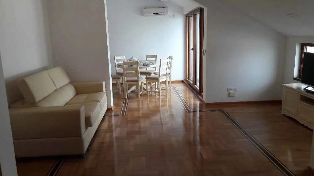Dnevna soba sa kožnom garniturom i trpezarijskim stolom.