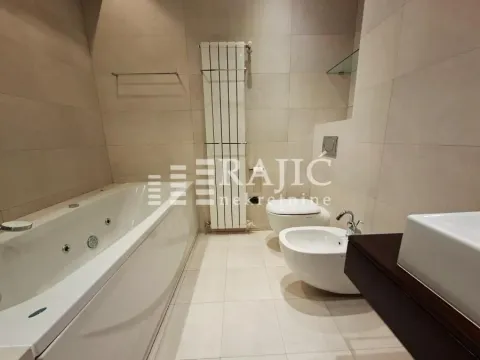 Modern bathroom with a bathtub, sanitary ware, and beige tiles. - image 9