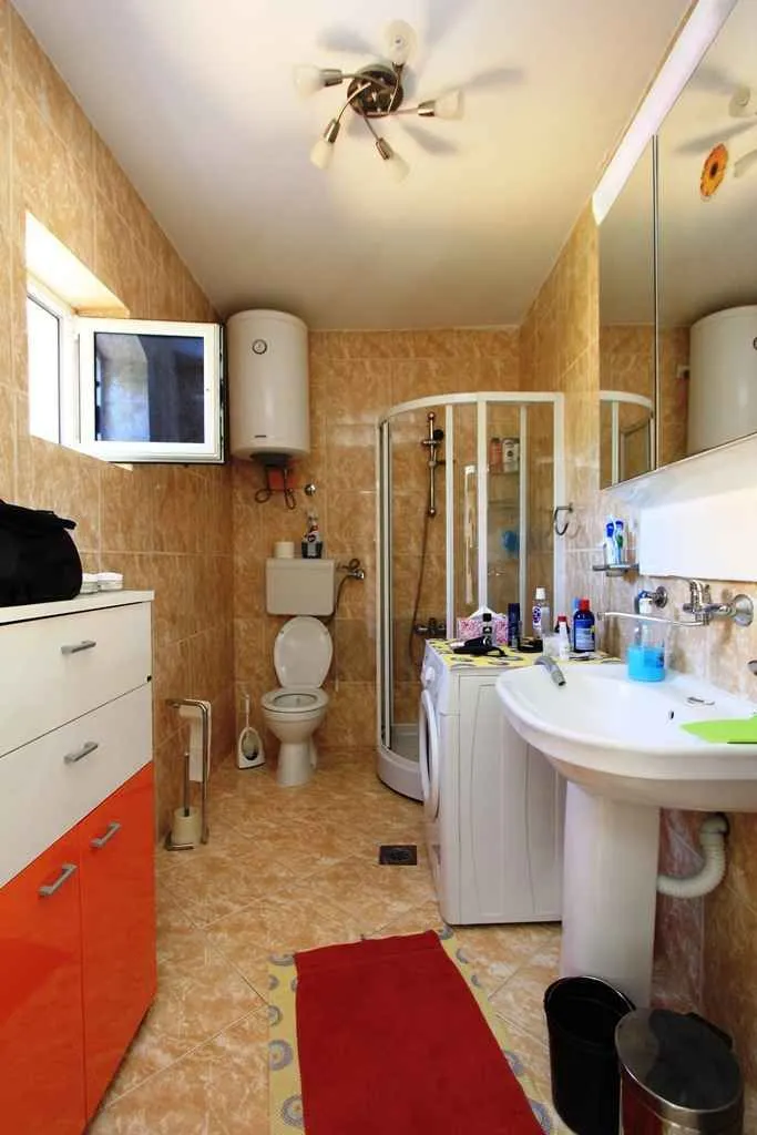 Svijetlo kupatilo sa tuš kabinom i veš mašinom.