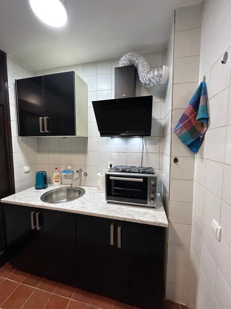 Small kitchen with a sink, mini oven, and black cabinets.