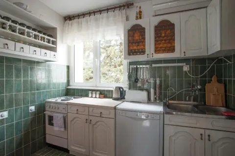 Small kitchen with white cabinets, green tiles, and a window. - image 15