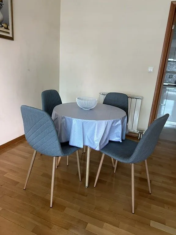 Trpezarijski sto sa četiri sive stolice u stanu.
