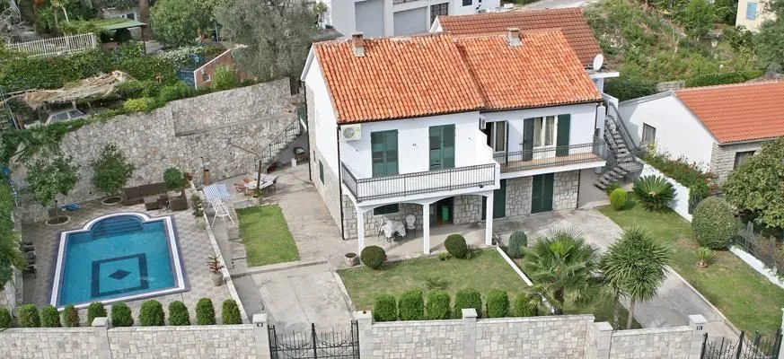 Pogled iz vazduha na dvospratnu kuću sa bazenom i uređenim dvorištem.