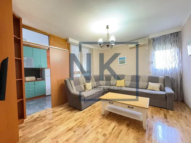 Dnevna soba sa garniturom, stočićem i pogledom na kuhinju.