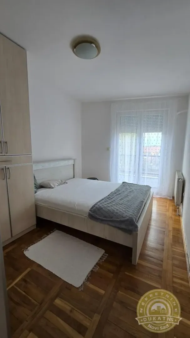 Spavaća soba sa bračnim krevetom, plakarom i prozorom.