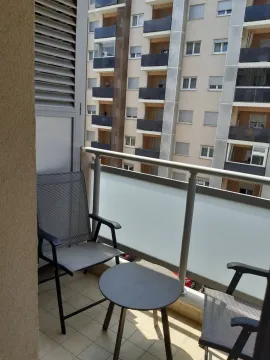 A balcony with two chairs and a table overlooking a neighboring building. - image 17