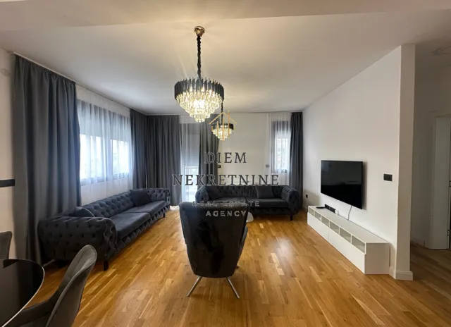 Spacious living room with sofa set, TV, and dining table.