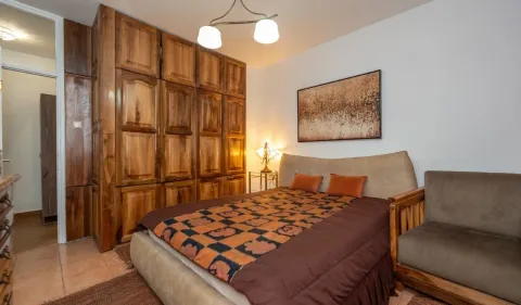 Bedroom with a large double bed, wooden wardrobe and an armchair. - image 6