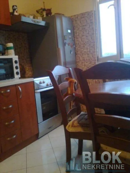 Kitchen with wooden cabinetry, a refrigerator, and a dining table with chairs.