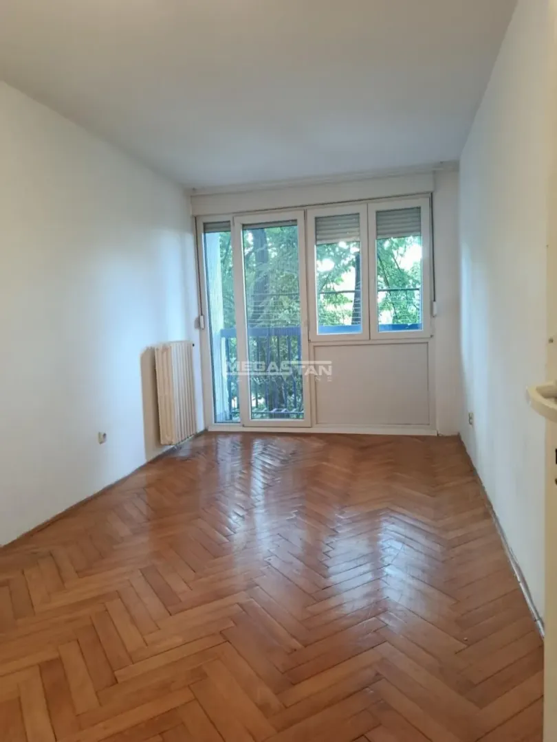 Prazna soba sa parketom i izlazom na terasu.