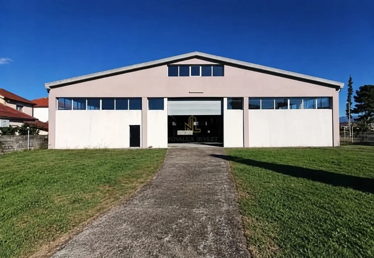 Exterior view of an industrial building with an access road and lawn.