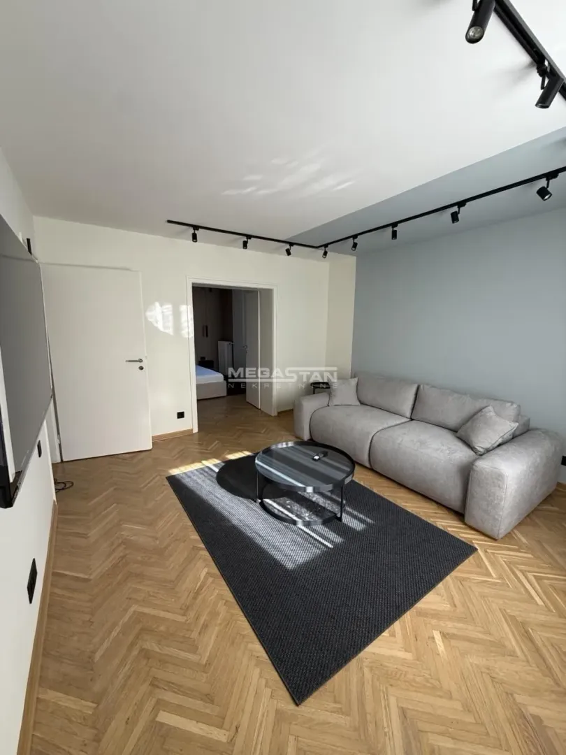 Living room with sofa, coffee table and parquet flooring.