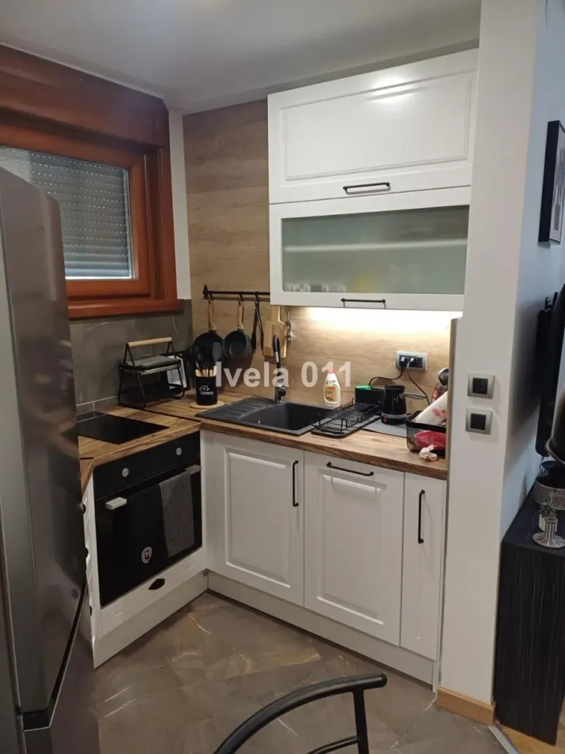 Small equipped kitchen with white cabinets and built-in appliances.