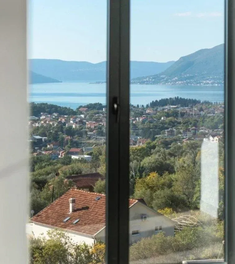 Pogled na more i okolno naselje kroz prozor.