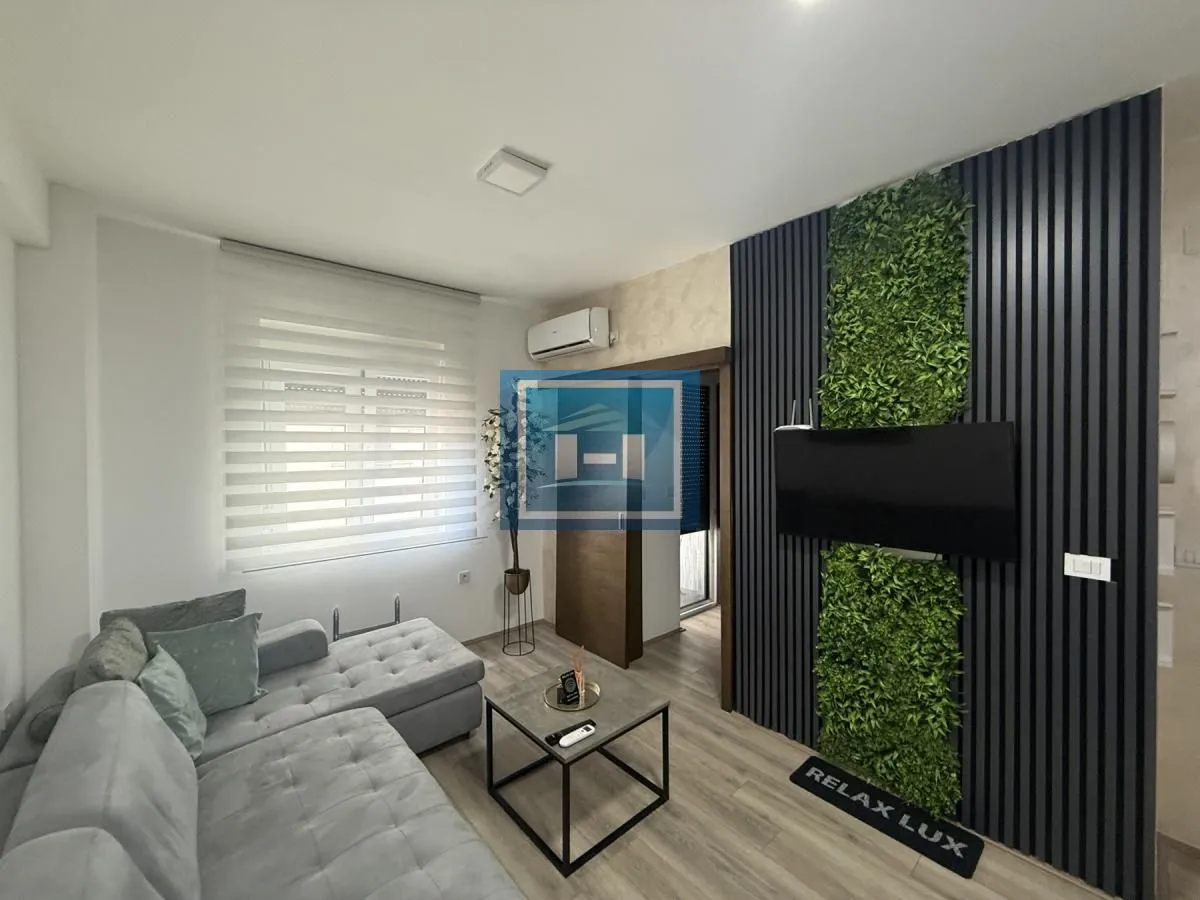 Living room with a sectional sofa, TV, and decorative wall panels.