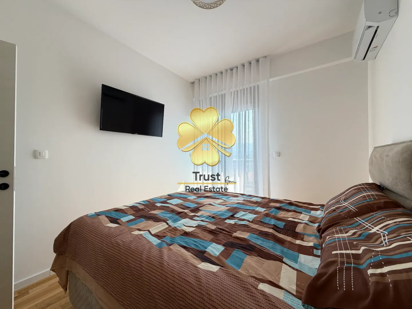 Furnished bedroom with a double bed, TV, and air conditioning.