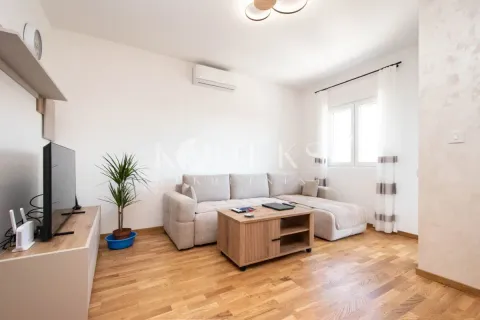 Living room with a sectional sofa, wooden coffee table, and television. - image 2