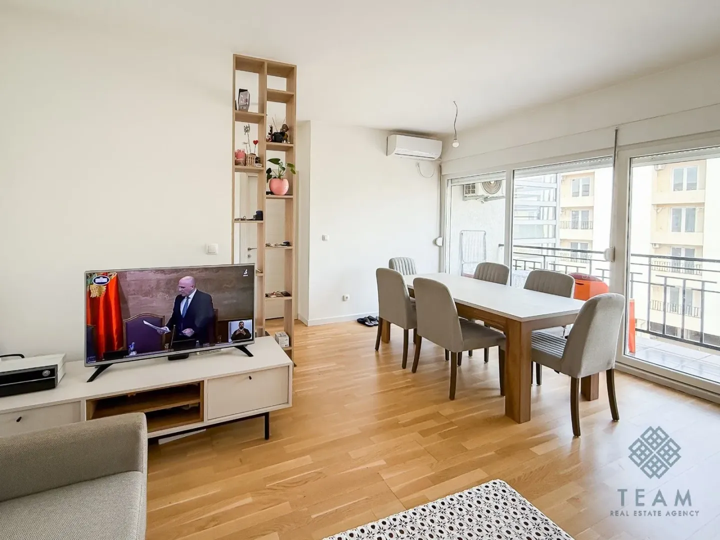Dnevni boravak sa trpezarijom, televizorom i izlazom na balkon.
