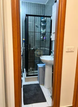 View of the bathroom with a shower cabin and washbasin through the doorway. - image 3