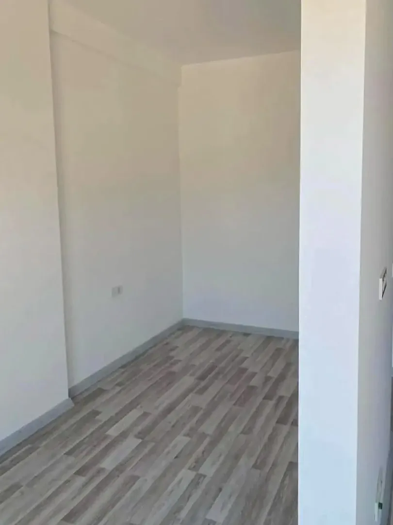 Prazna soba sa bijelim zidovima i laminatnim podom.