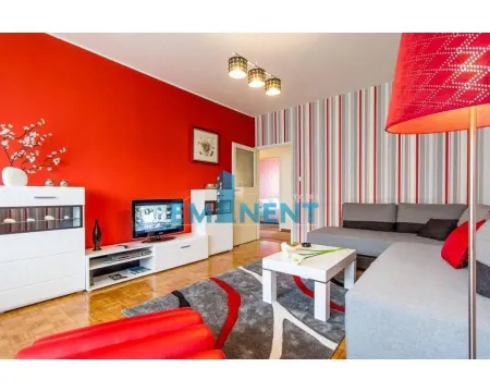 Living room with a sofa set, television, and a red wall. - image 2