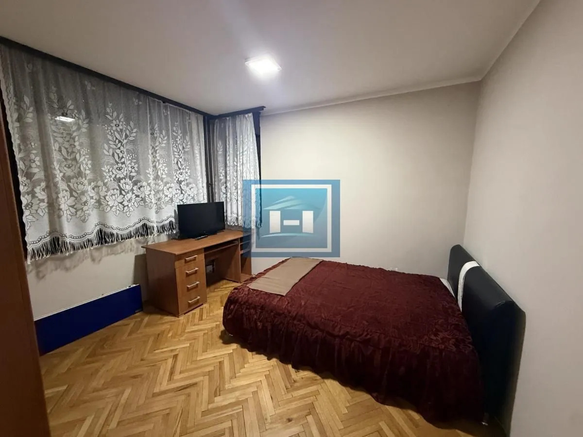 Furnished bedroom with a double bed, desk, and parquet flooring.
