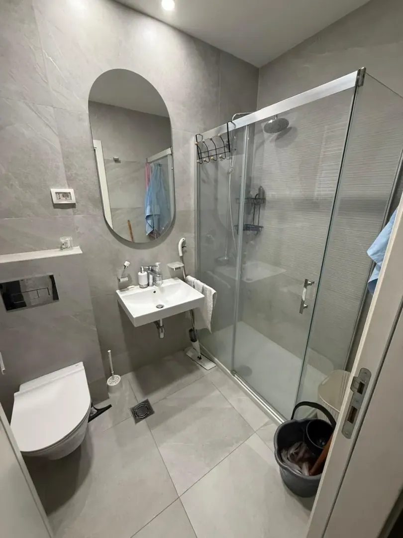 Modernly equipped bathroom with a walk-in shower and grey tiles.