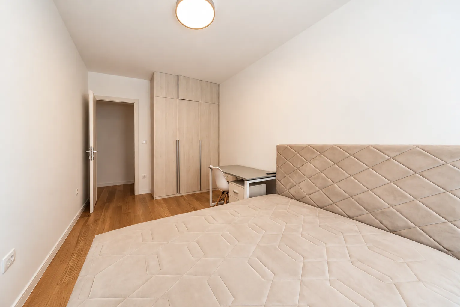 Furnished bedroom with a double bed, wardrobe, and a desk.