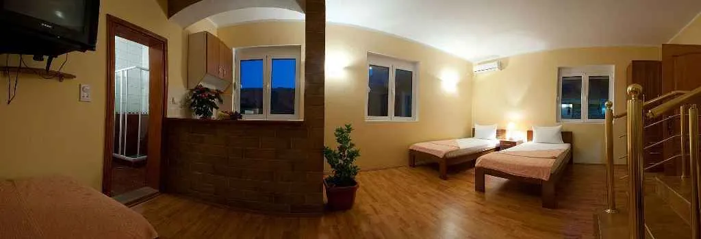 Svijetla soba u studio apartmanu sa dva singl kreveta i kuhinjskim dijelom.