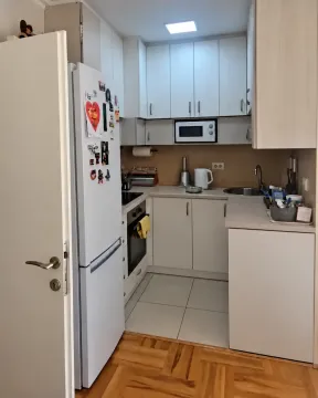 Manja svijetla kuhinja sa bijelim elementima i bijeli frižider sa magnetima. - image 11
