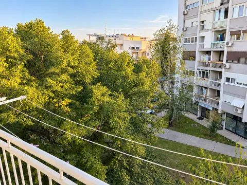 View from the balcony overlooking surrounding greenery and a building. - image 8