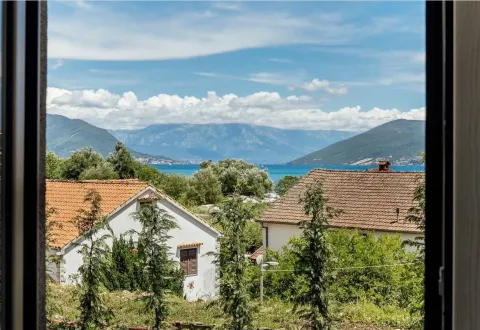 Pogled kroz prozor na more, kuće i planine u daljini. - image 11