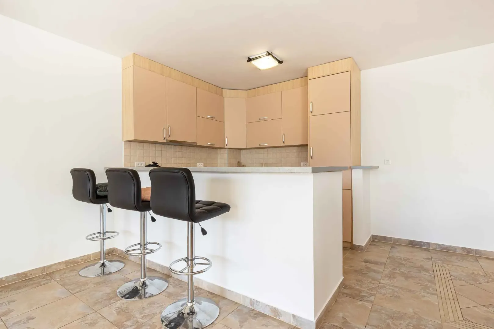 Kitchen with wood-tone cabinetry and a breakfast bar with bar stools.