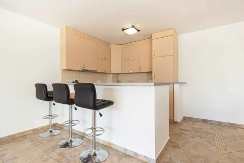 Kitchen with wood-tone cabinetry and a breakfast bar with bar stools. - image 8