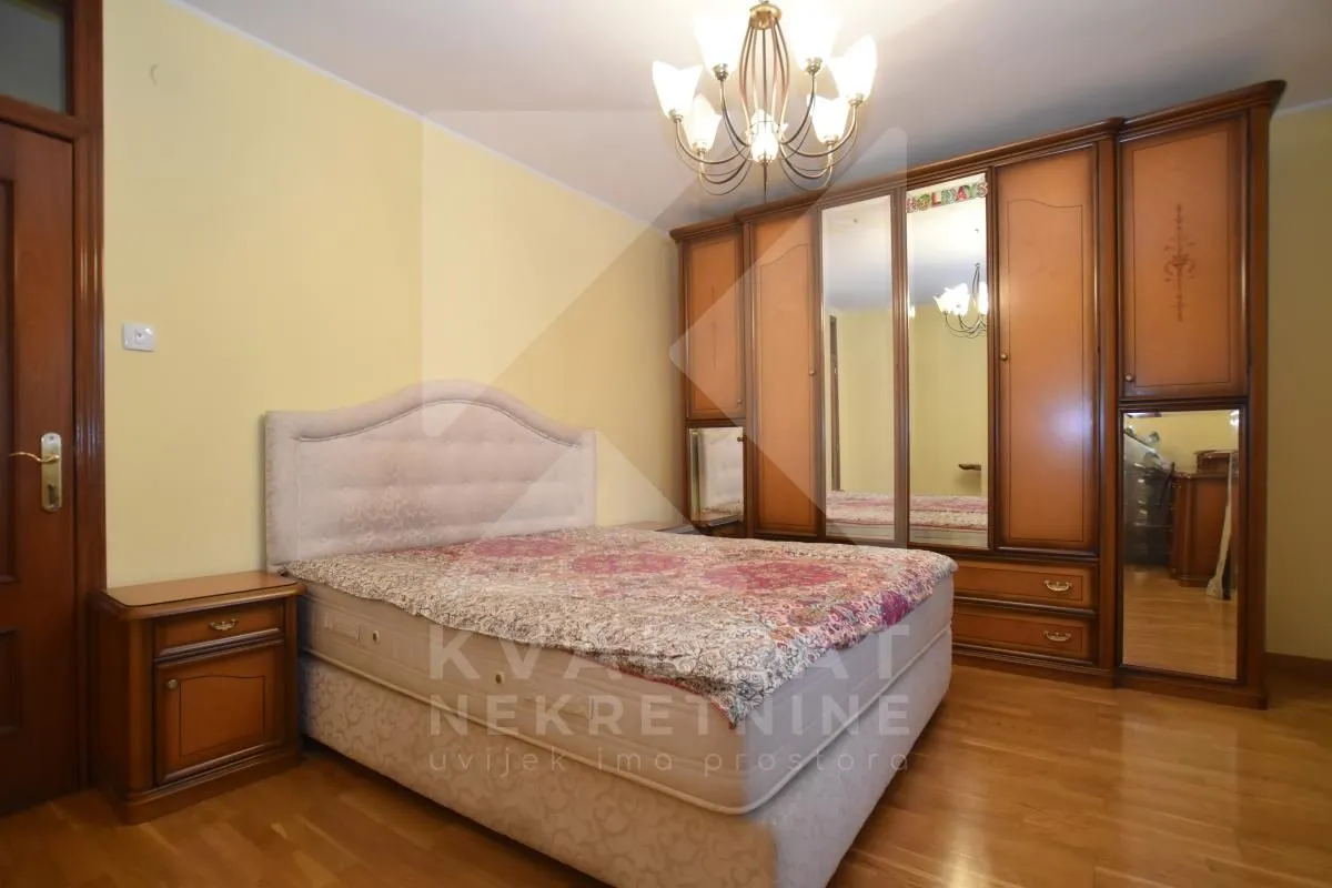 Bedroom with a double bed, large wooden wardrobe, and bedside table.