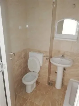 Jednostavno kupatilo sa bež pločicama, toaletom i lavaboom. - image 20