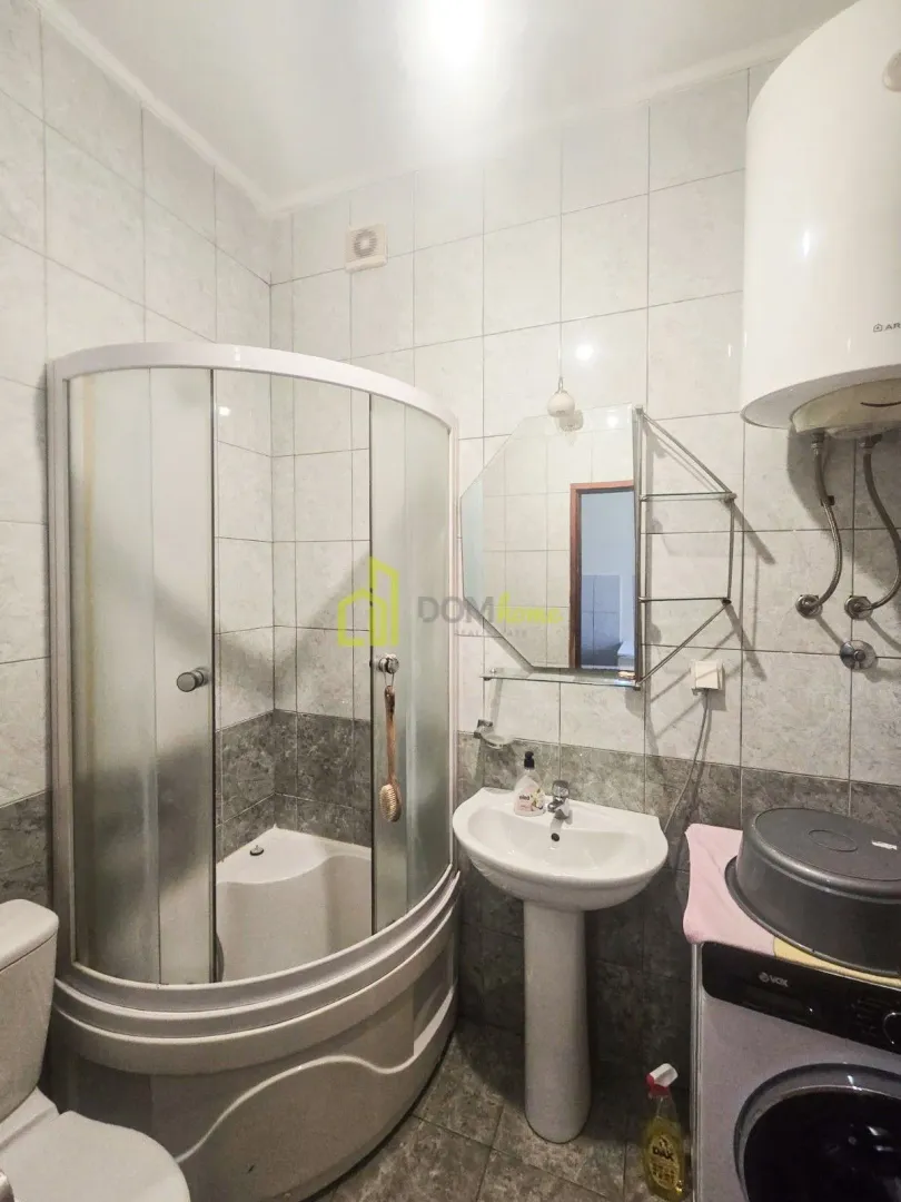 Bathroom equipped with a shower cabin, sink, mirror, and washing machine.