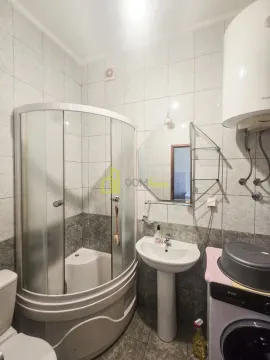 Bathroom equipped with a shower cabin, sink, mirror, and washing machine. - image 2