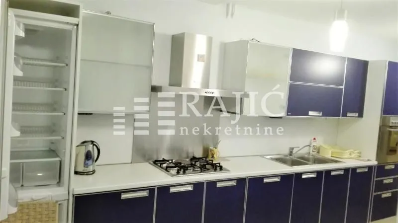 Moderna kuhinja sa plavim elementima i ugrađenim uređajima.