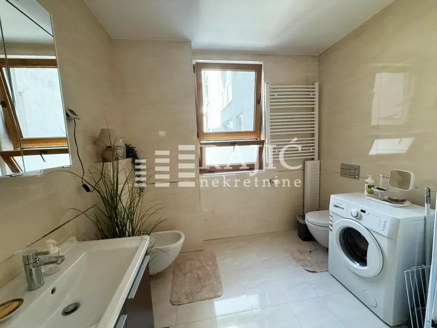 Spacious bathroom with sanitary ware, washing machine, and window.